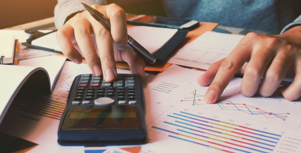 Man using calculator and looking at graphs